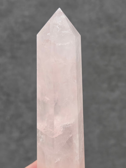 rose quartz crystal point with a gray background