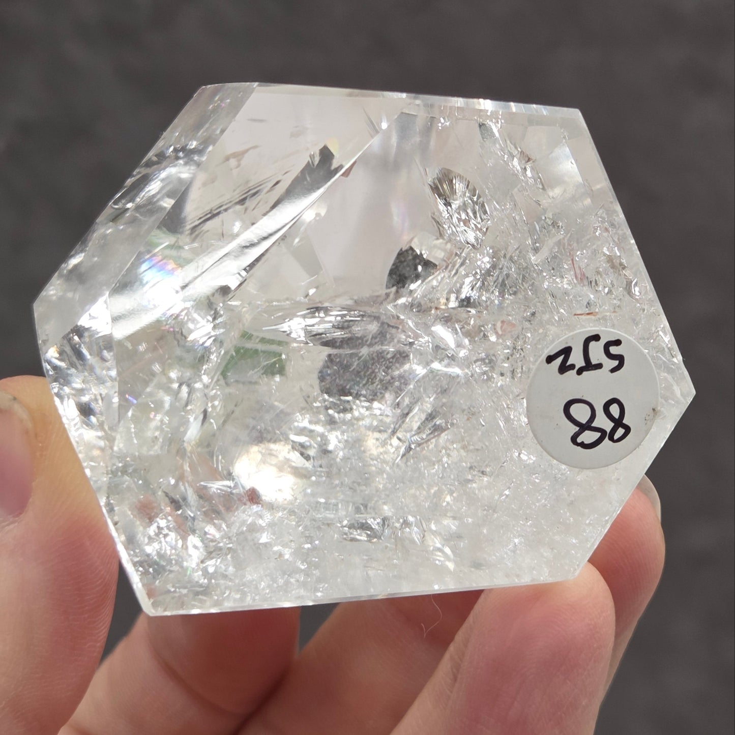Bottom of a clear quartz tower held in a hand against a dark background