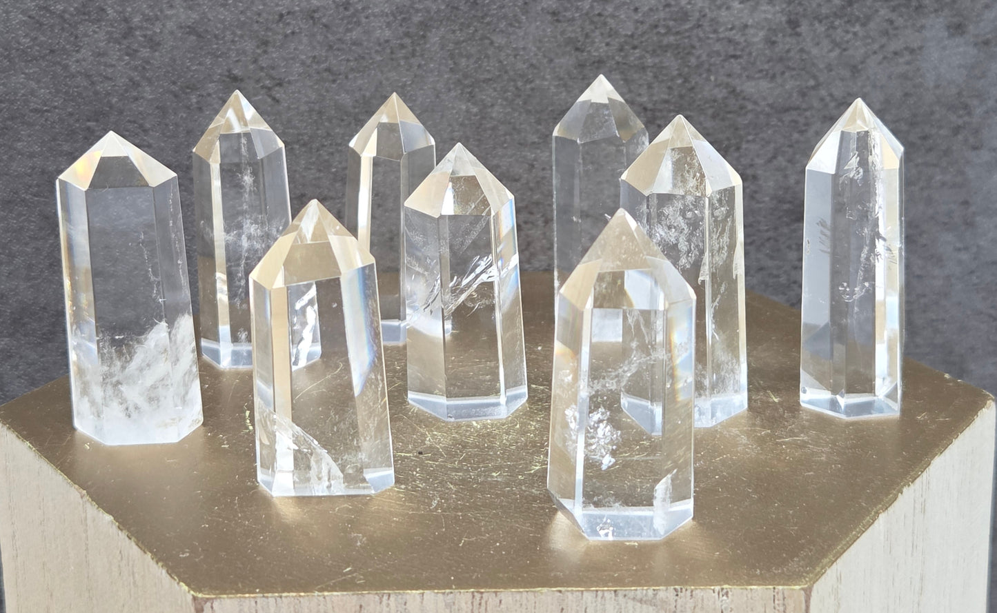 Clear crystal points on a wooden stand against a dark gray background