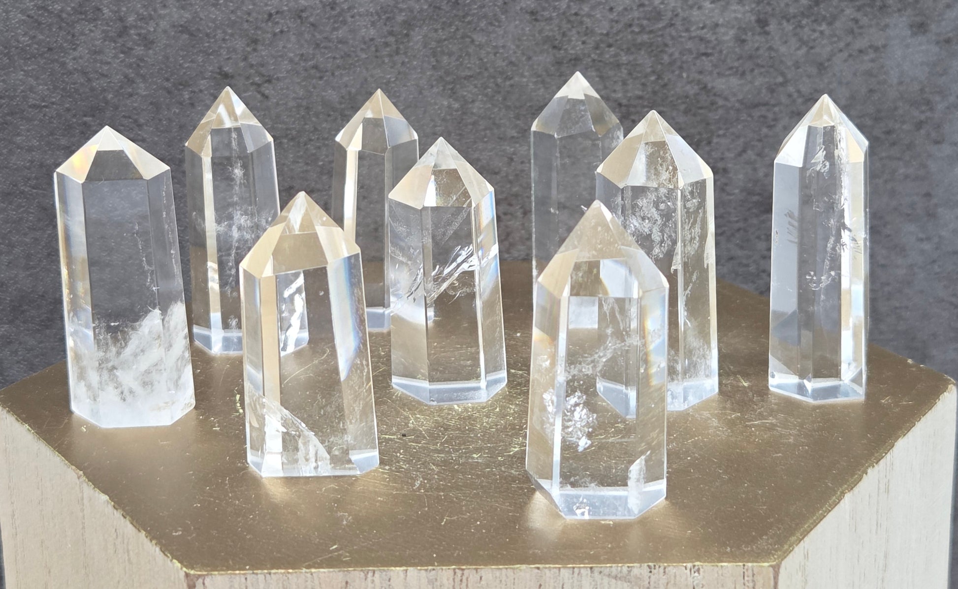 Clear crystal points on a wooden stand against a dark gray background