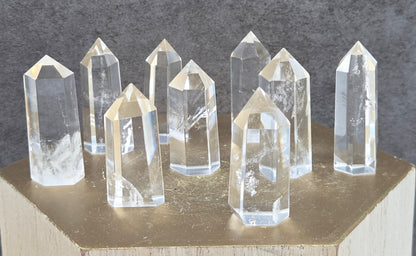 Clear crystal points on a wooden stand against a dark gray background