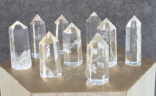 Clear crystal points on a wooden stand against a dark gray background