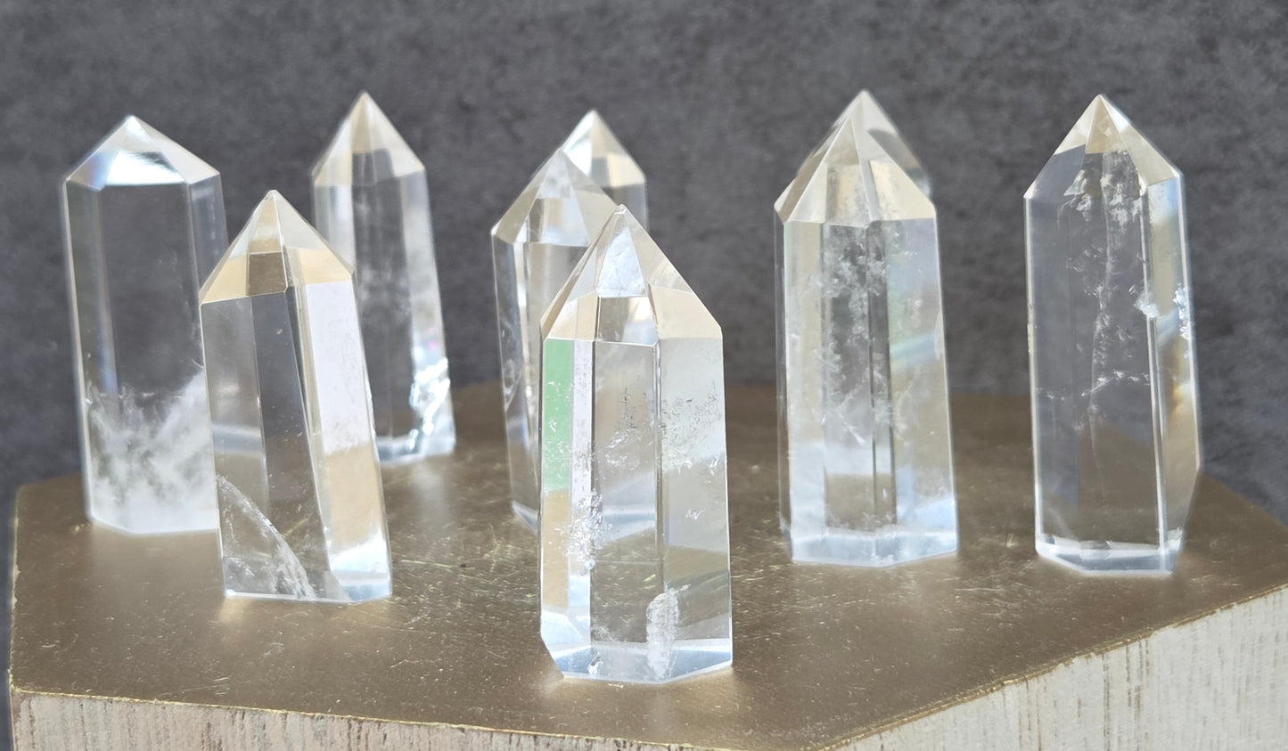 Clear crystal points on a wooden stand against a dark background