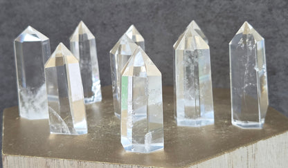 Clear crystal points on a wooden stand against a dark background