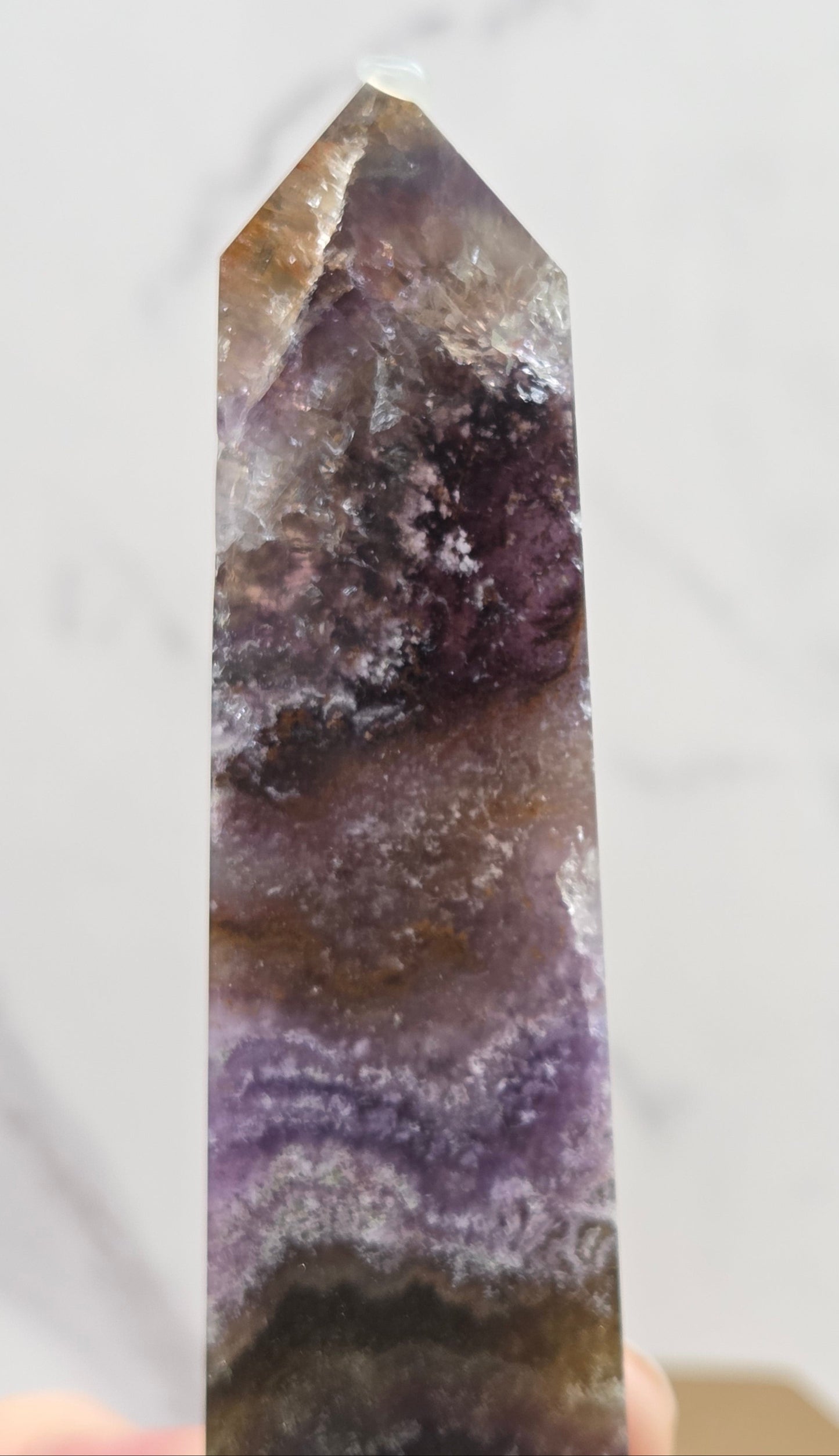Polished crystal with purple and brown hues on a white background