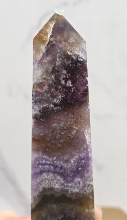 Polished crystal with purple and brown hues on a white background