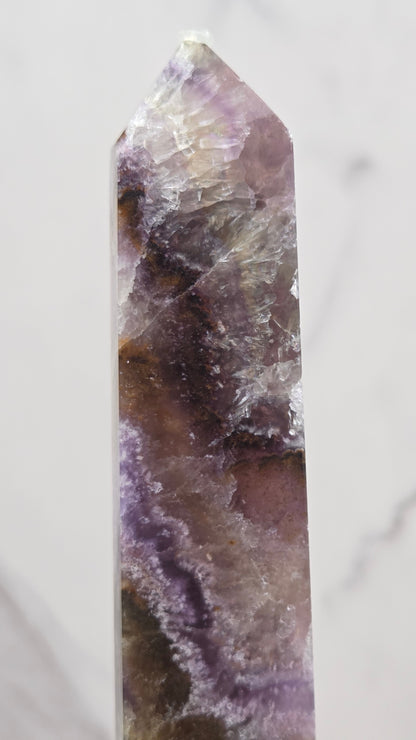 Crystal with purple and brown colors on a marble surface