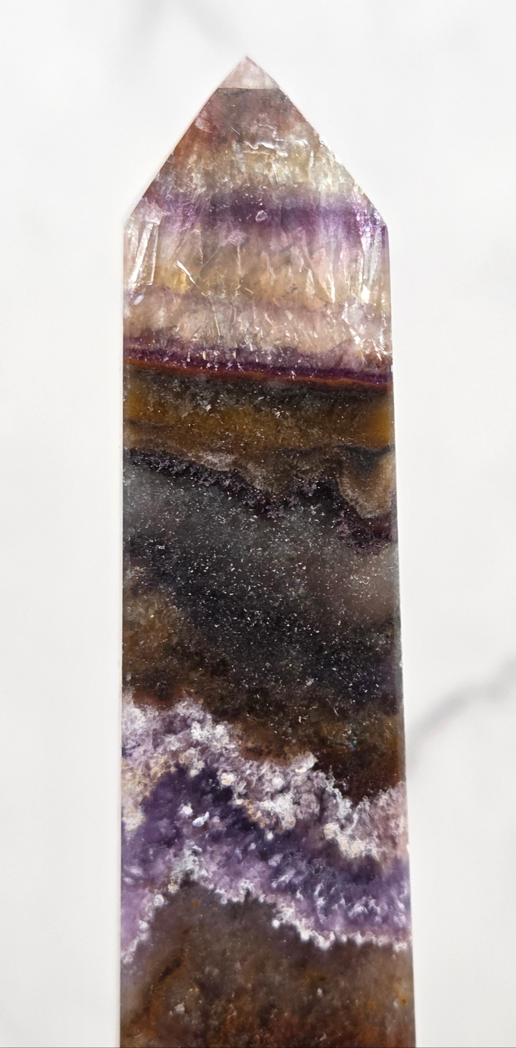 Close-up of a multicolored crystal with purple and brown hues on a white background