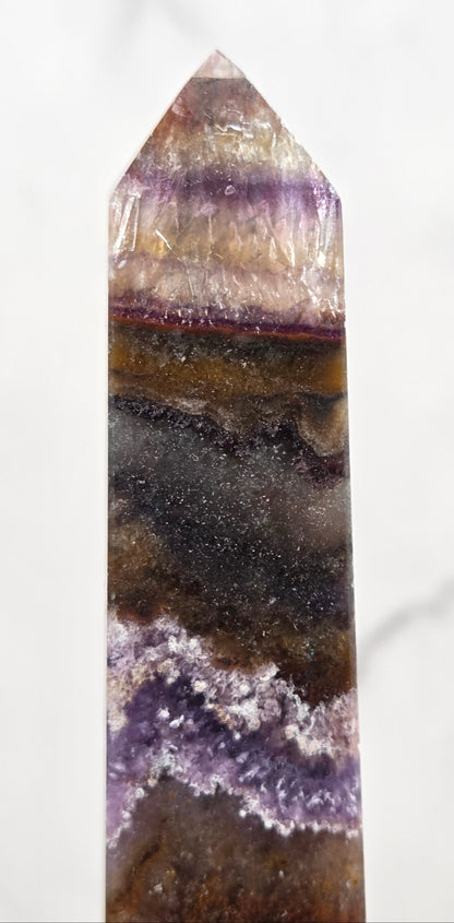 Close-up of a multicolored crystal with purple and brown hues on a white background