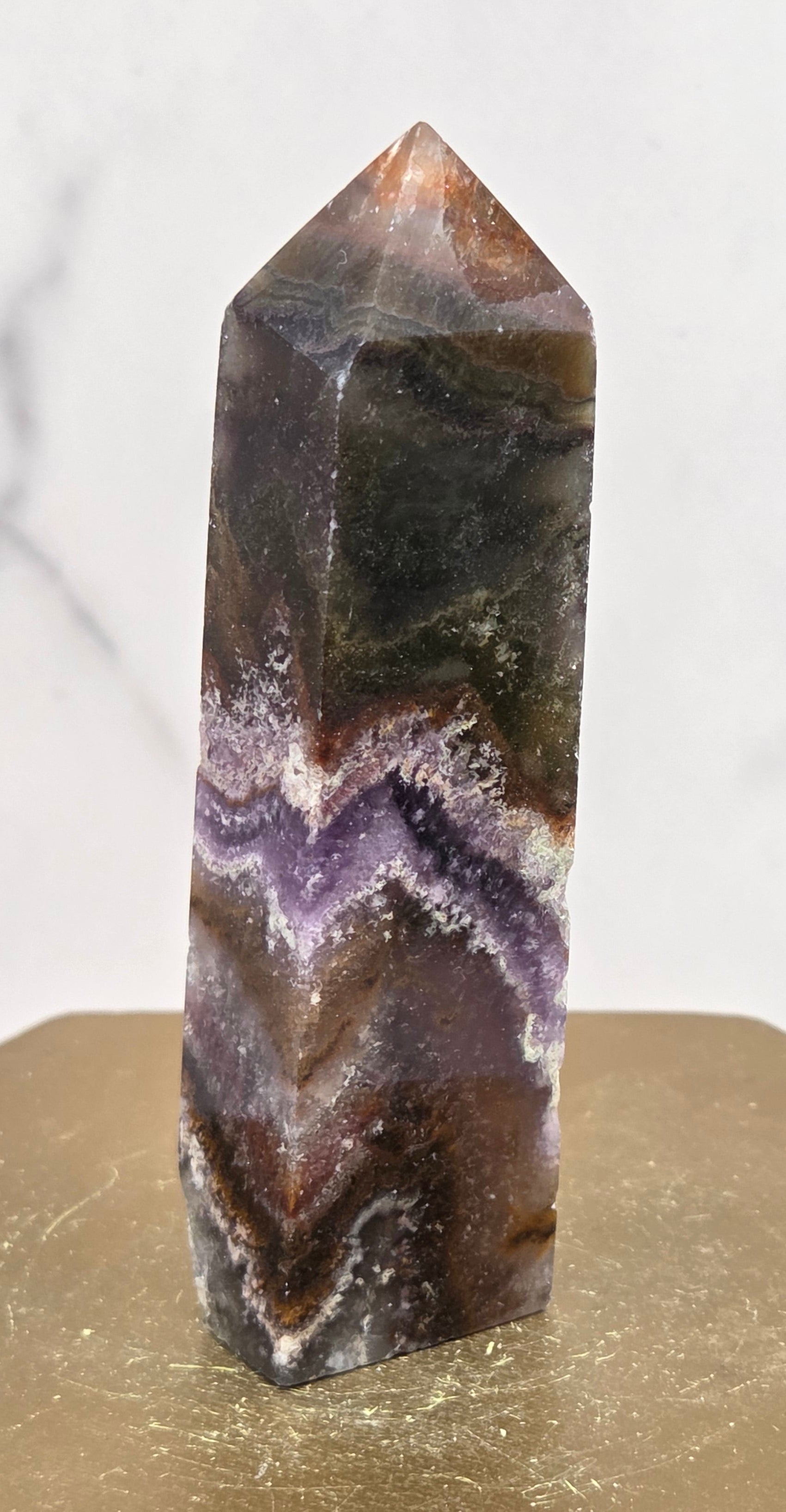 Polished crystal with purple and brown patterns on a white marble background