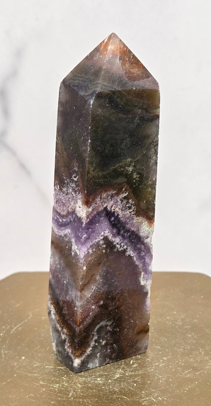 Polished crystal with purple and brown patterns on a white marble background