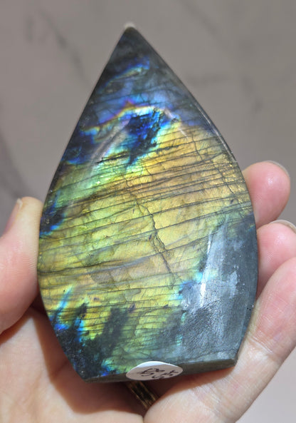 Hand holding a labradorite stone with colorful patterns