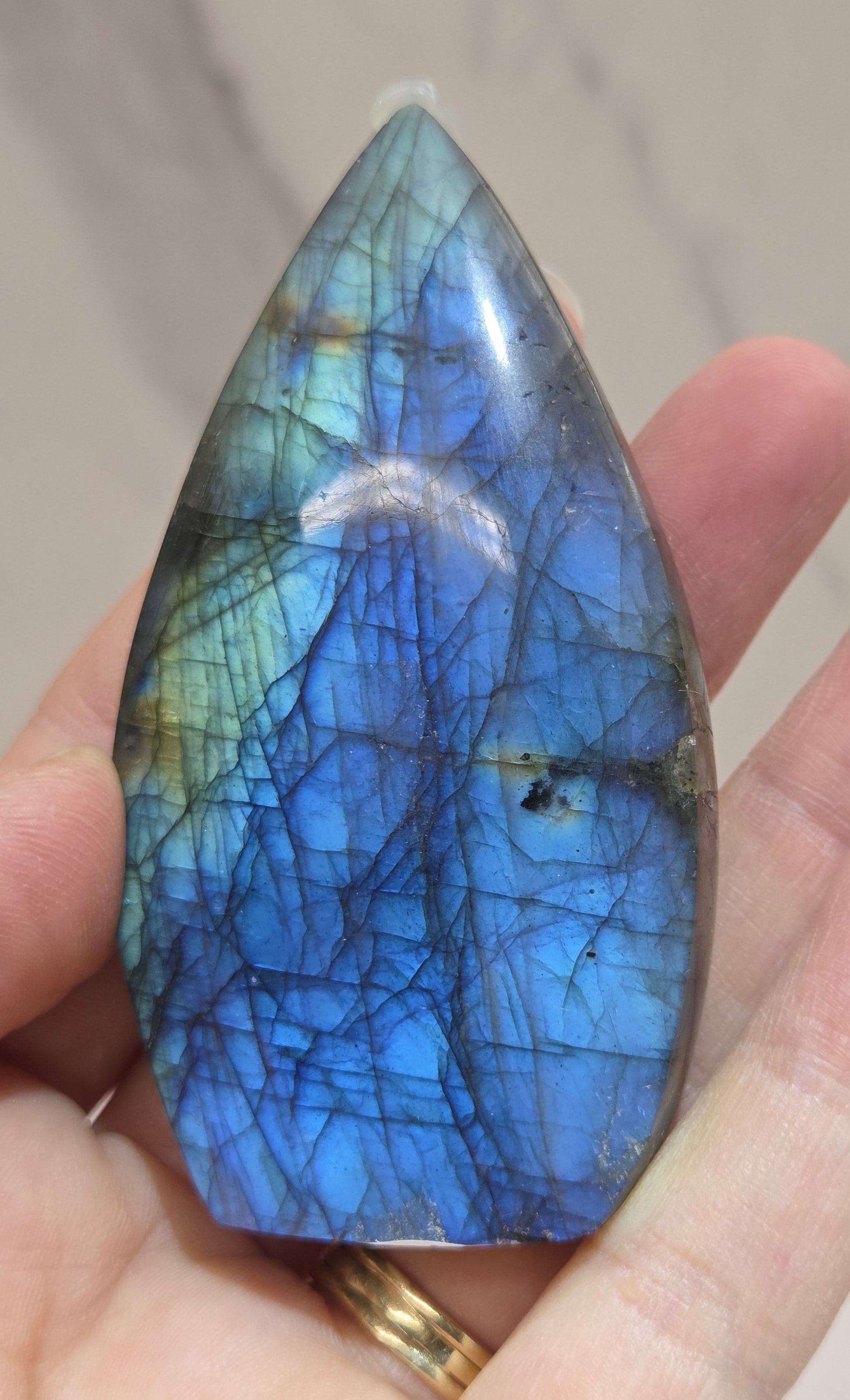 Hand holding a labradorite stone with blue and green patterns