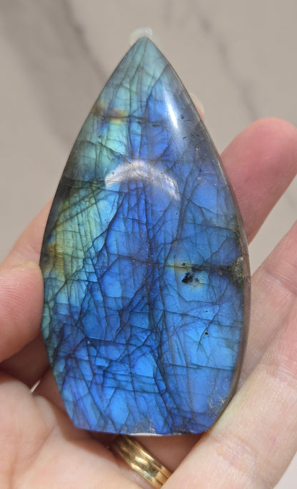 Hand holding a labradorite stone with blue and green patterns