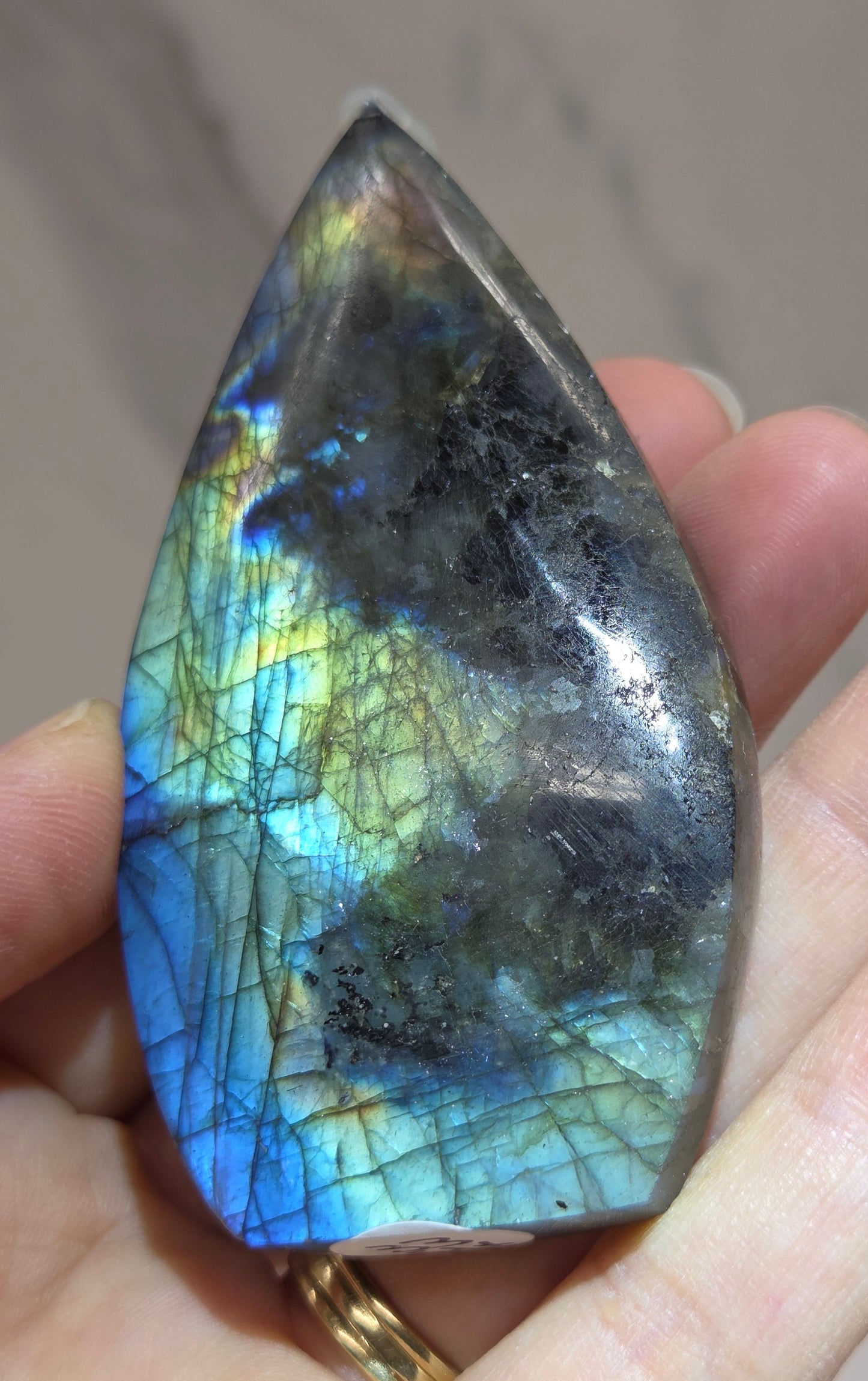 Hand holding a labradorite stone with colorful patterns