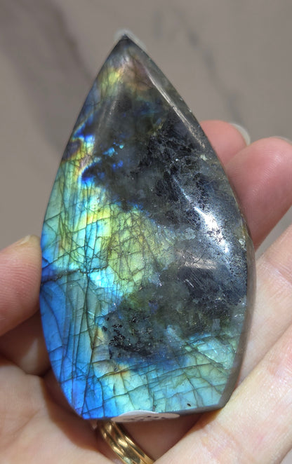 Hand holding a labradorite stone with colorful patterns