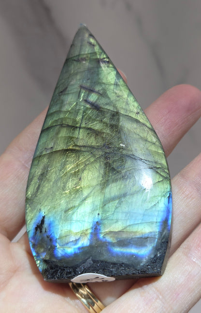 Labradorite stone held in a hand with a blurred background