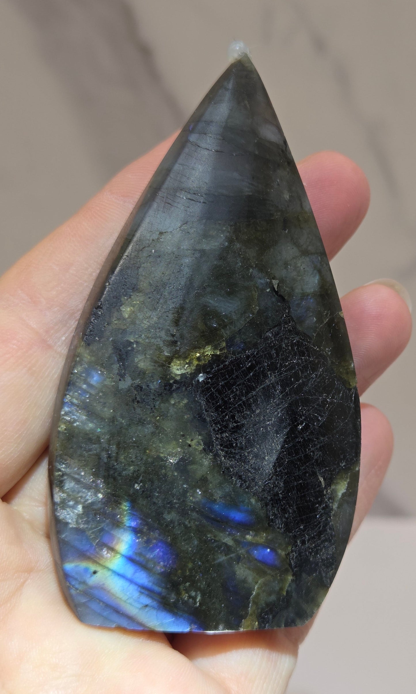 Labradorite stone held in a hand against a neutral background