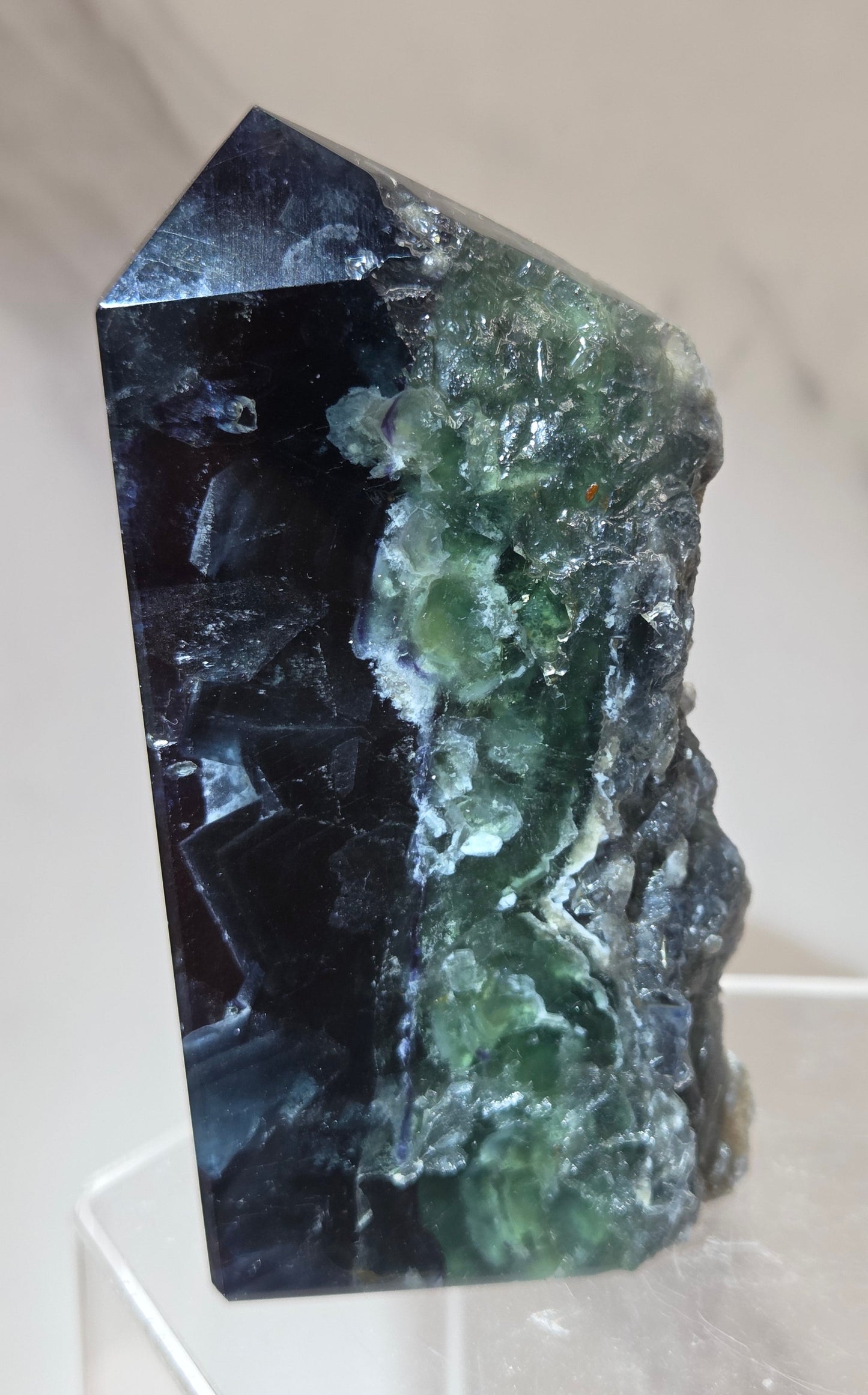 Fluorite tower with green and dark blue colors on a white surface