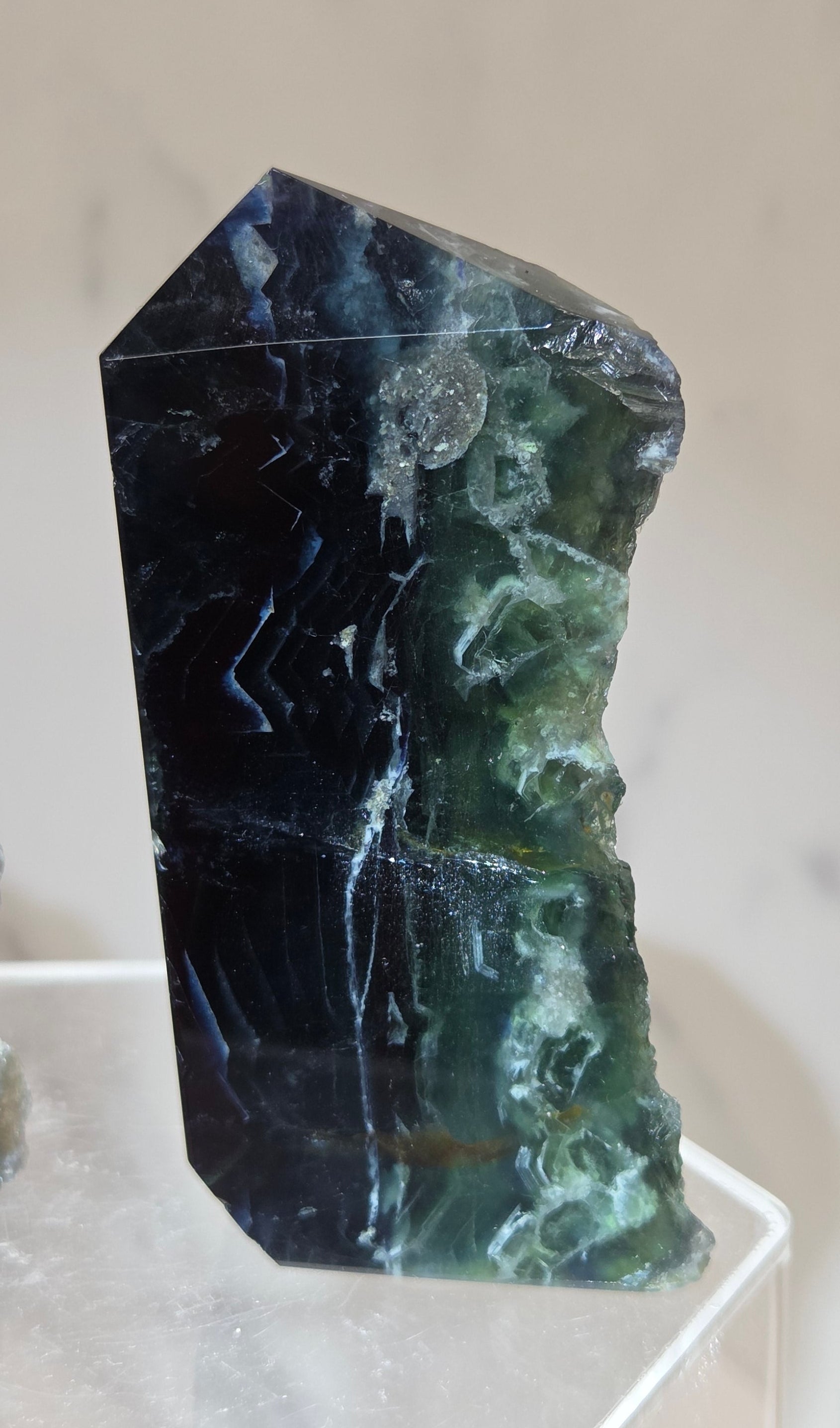 Fluorite tower with green and dark blue colors on a white surface