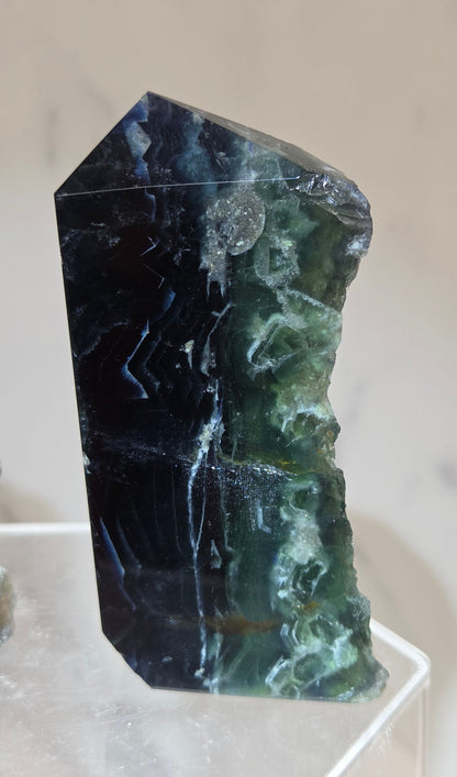 Fluorite tower with green and dark blue colors on a white surface