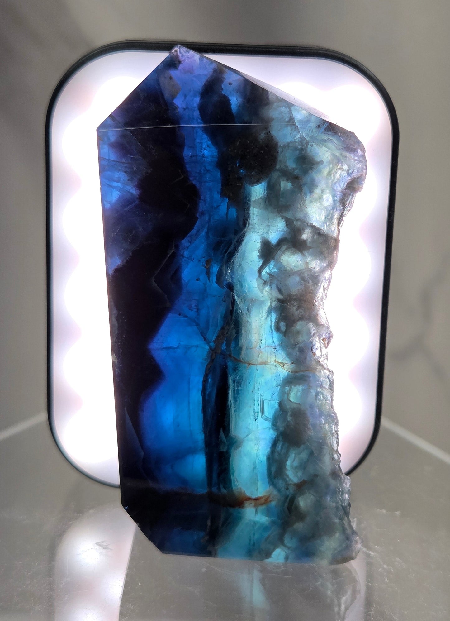 Backlit Fluorite tower with green and dark blue colors on a white surface