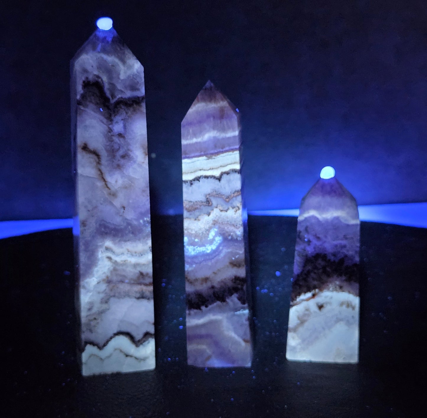 Crystal with purple and brown colors  on a dark surface under UV light