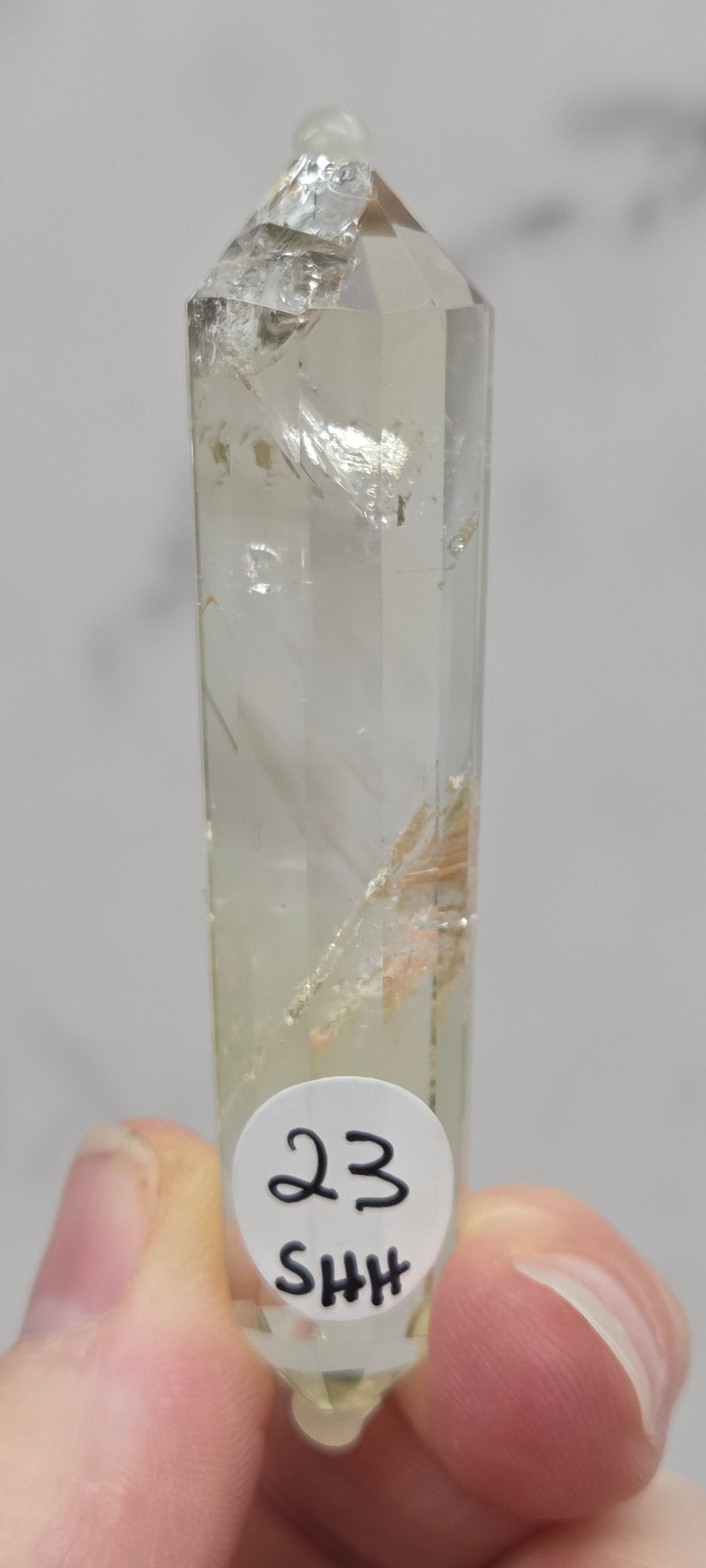 Crystal held by a hand with a label on a marble background