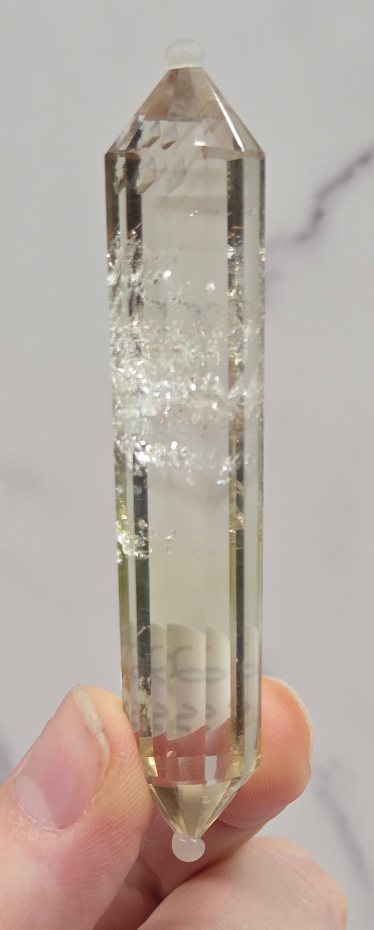 Clear crystal held by a hand on a marble background