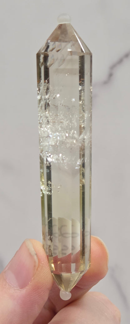 Clear crystal held by a hand on a marble background