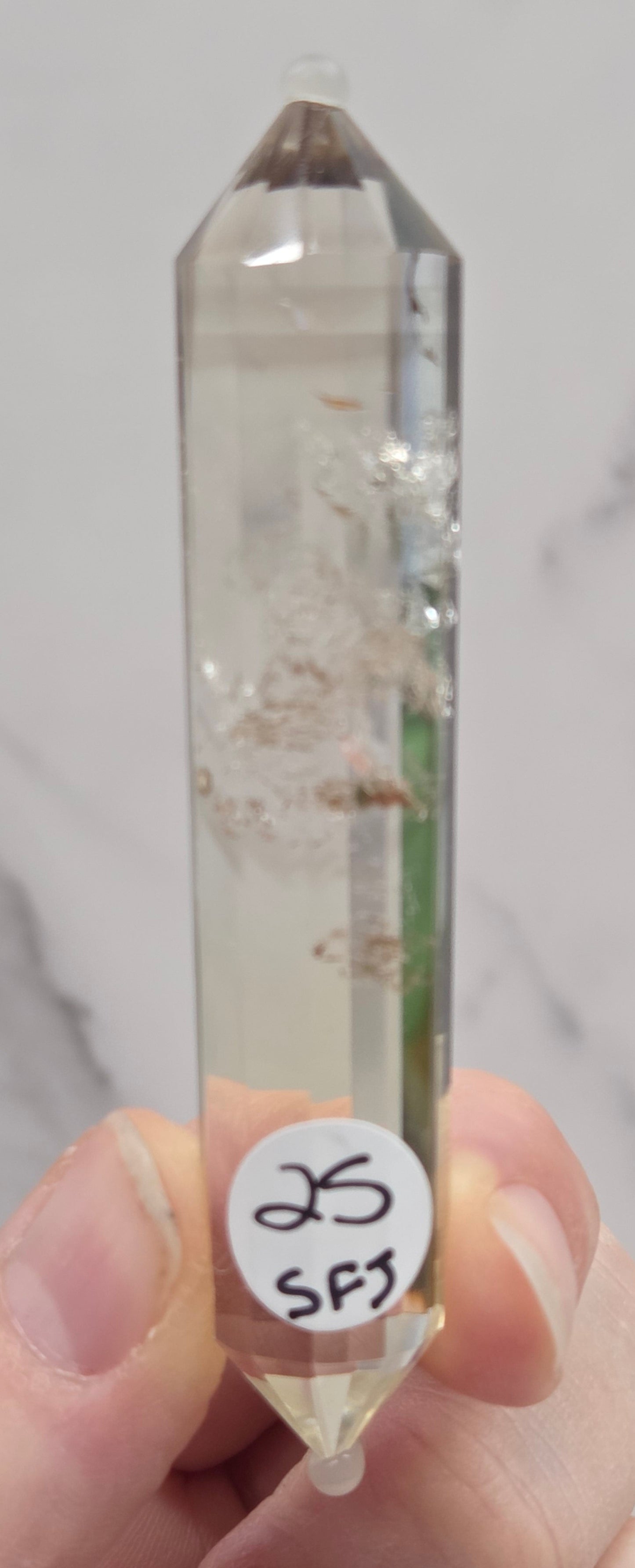 Crystal with a label held by a hand against a marble background