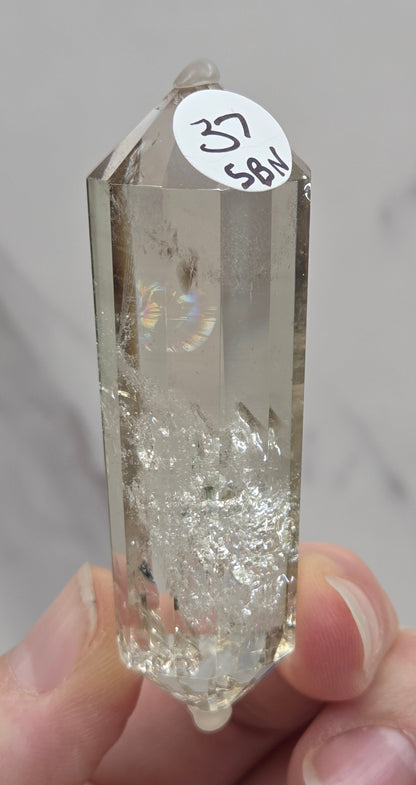 Crystal with a label held by a hand against a neutral background