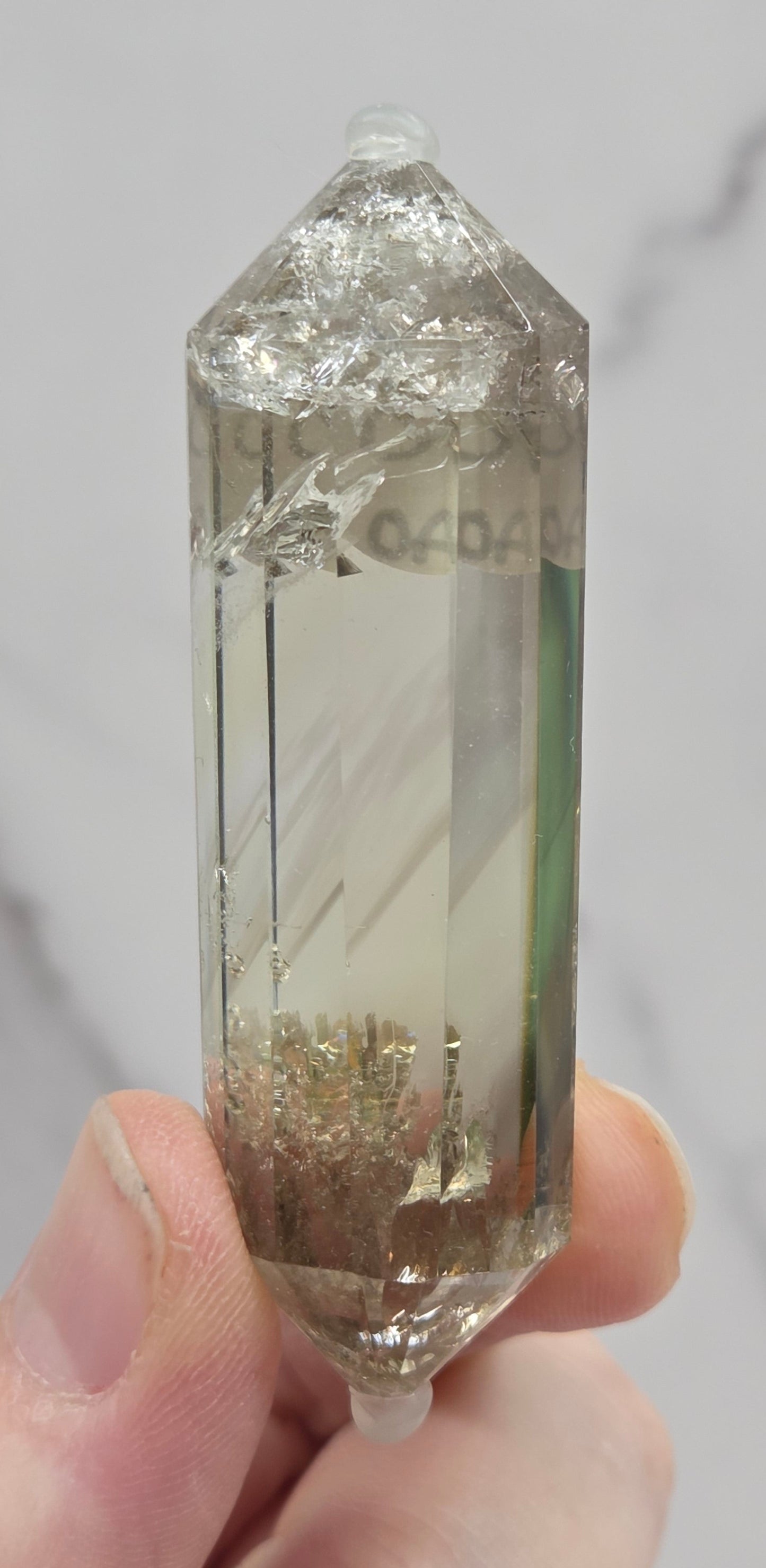 Hand holding a crystal with a light gray background