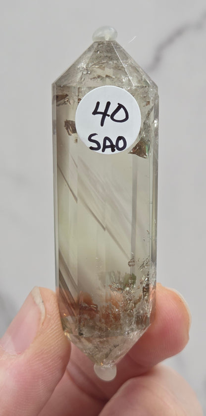 Crystal held by a hand with a label on a light gray background
