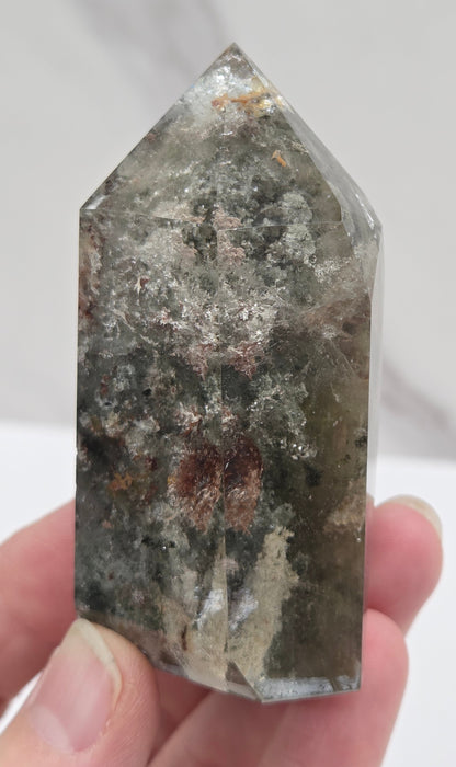 Hand holding a Garden Quartz crystal with a white background