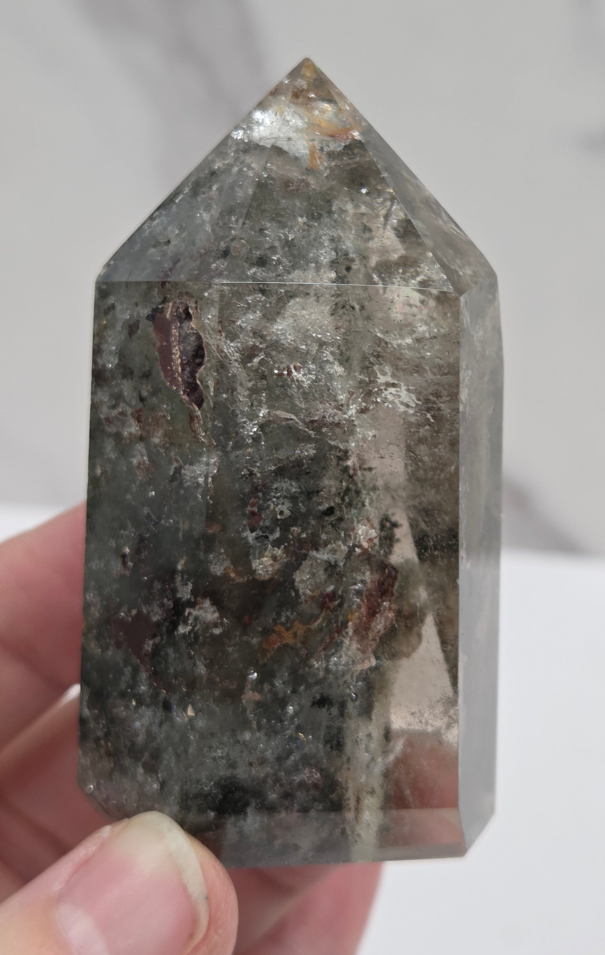 Person holding a Garden Quartzcrystal with a gray and brown color pattern against a neutral background