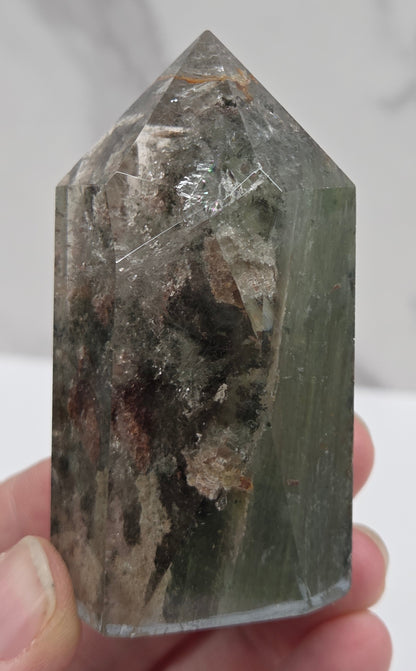 Person holding a Garden Quartz crystal with a white background