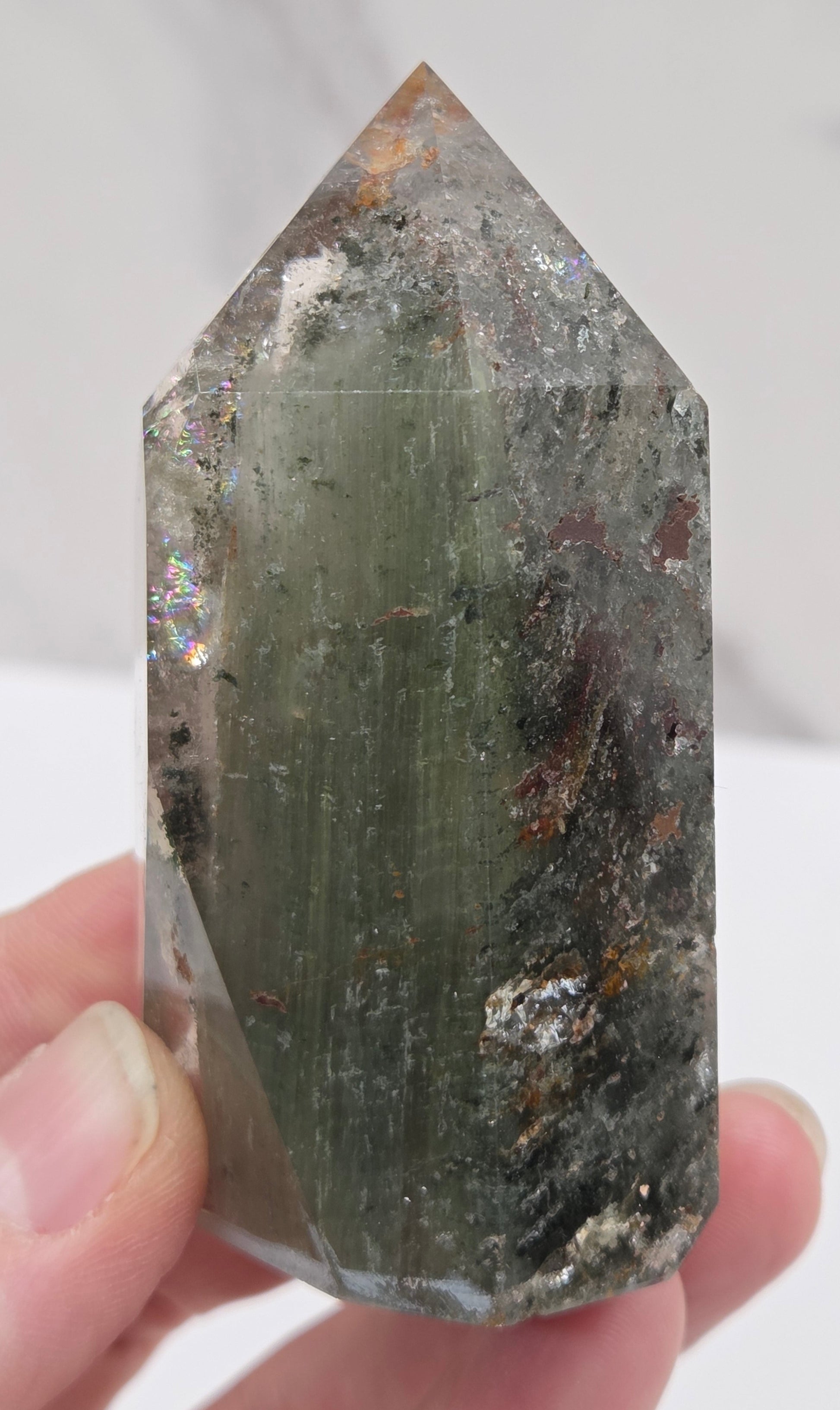 Garden Quartz crystal held by a hand against a white background