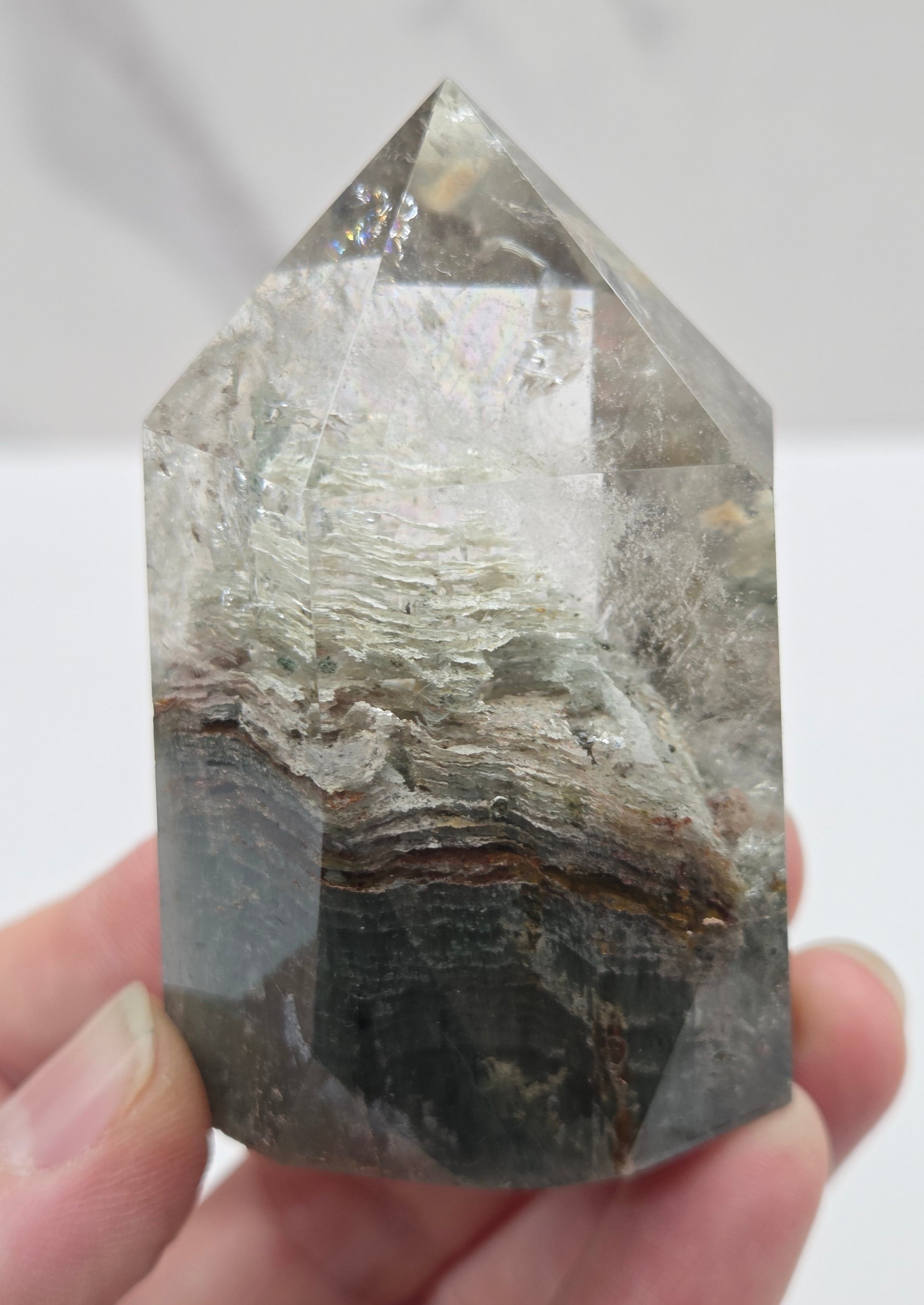 Hand holding a Garden Quartz crystal with a white background
