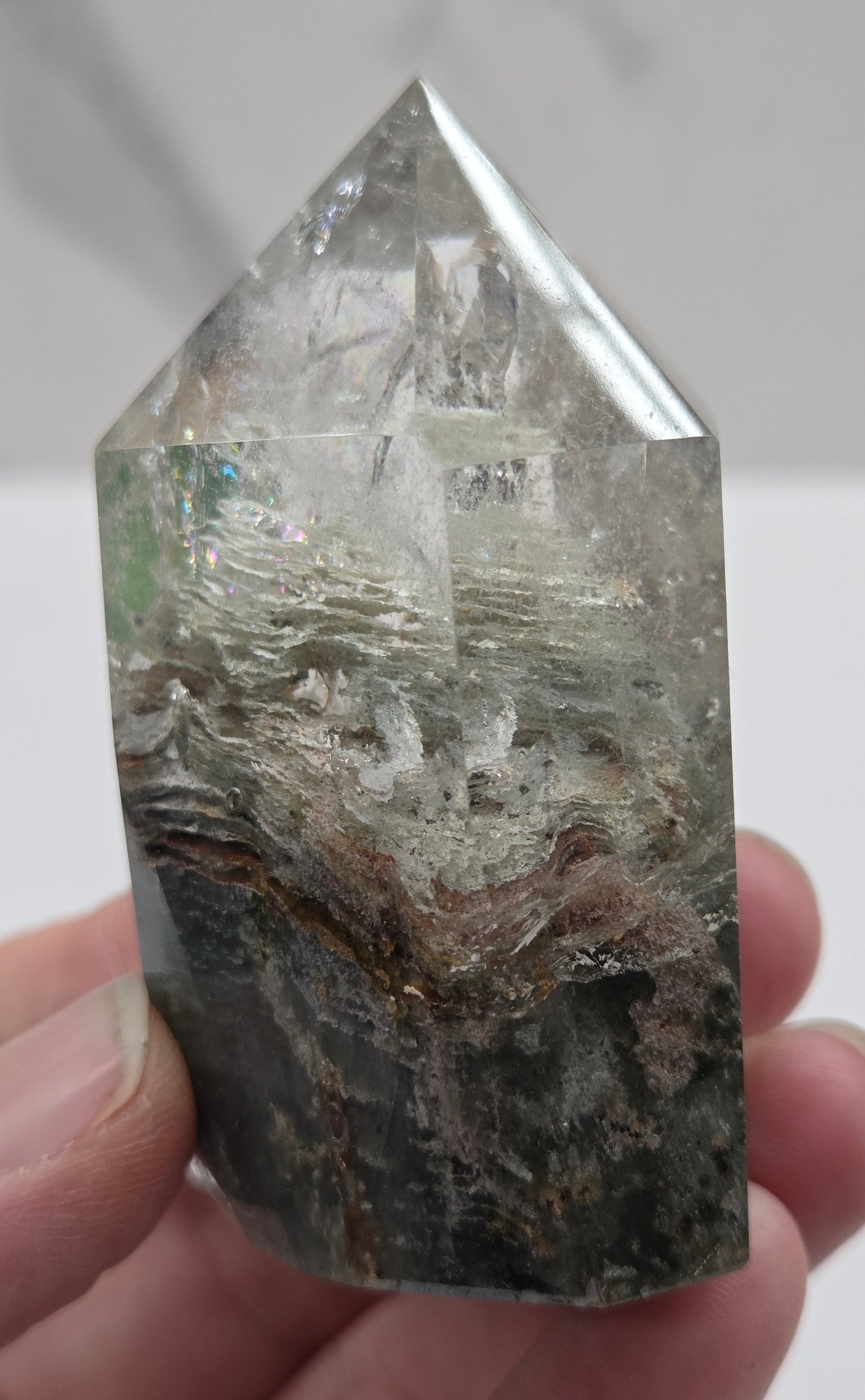 Hand holding a Garden Quartz crystal with a white background