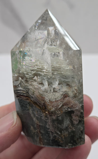 Hand holding a Garden Quartz crystal with a white background