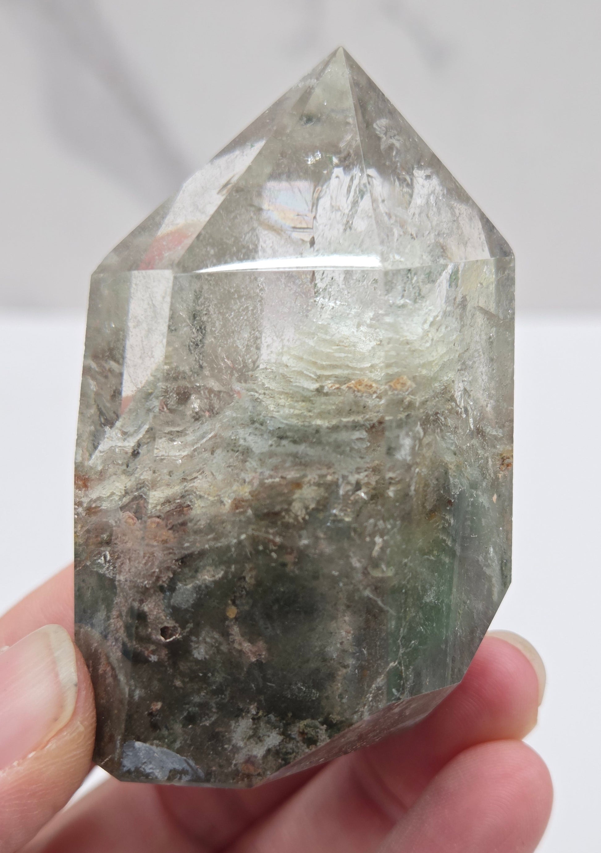Hand holding a Garden Quartz crystal with a white background