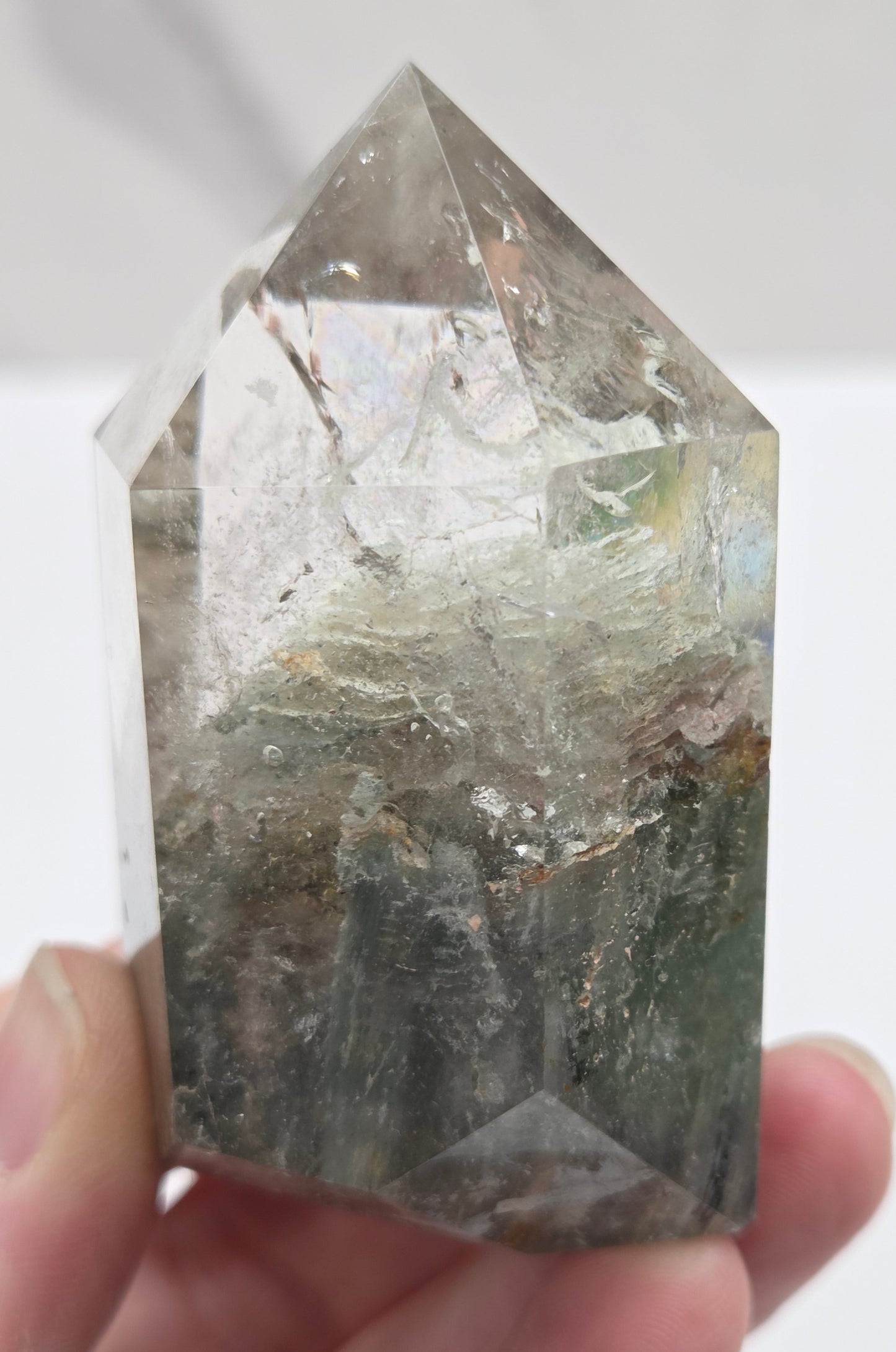 Hand holding a Garden Quartz crystal with a white background