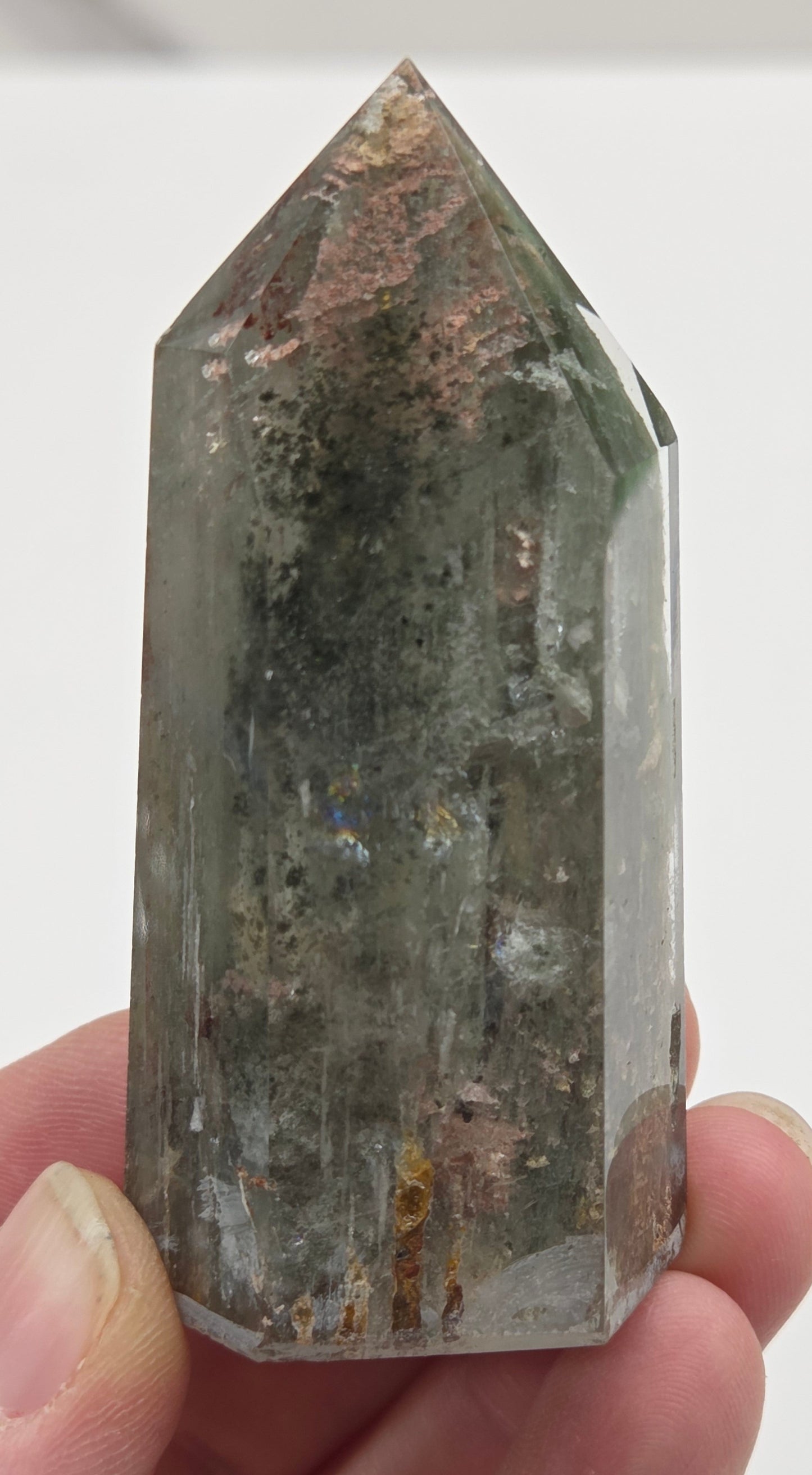 Hand holding a Garden Quartz crystal with a white background