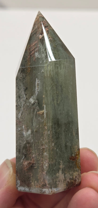 Hand holding a Garden Quartz crystal point against a white background