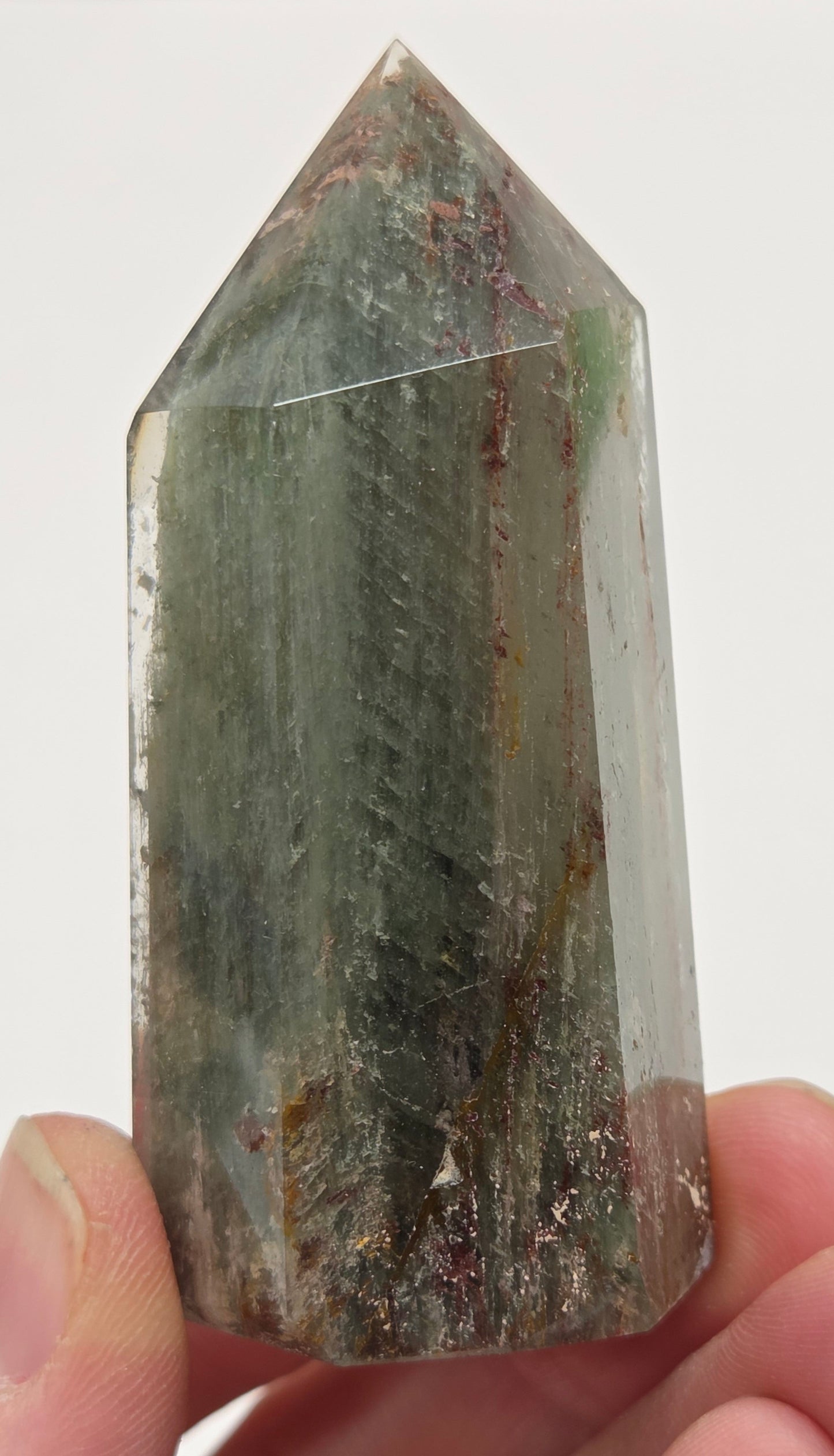 Hand holding a Garden Quartz crystal with a white background