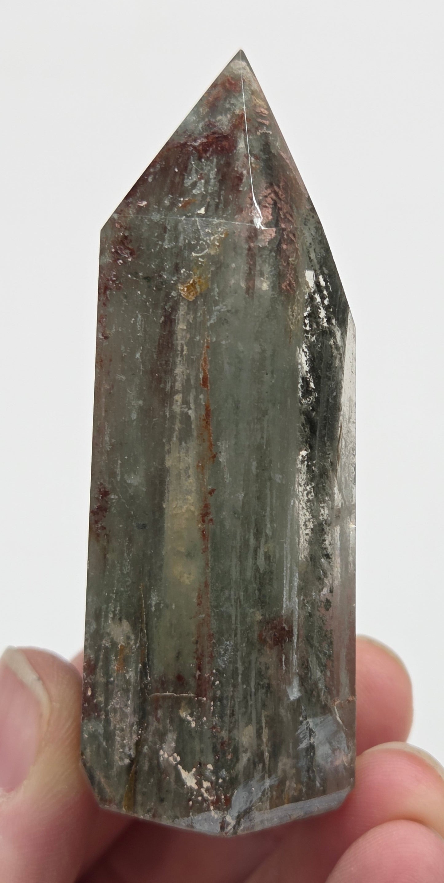 Hand holding a Garden Quartz crystal with a white background