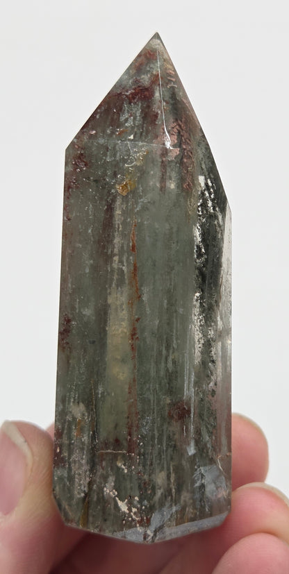 Hand holding a Garden Quartz crystal with a white background