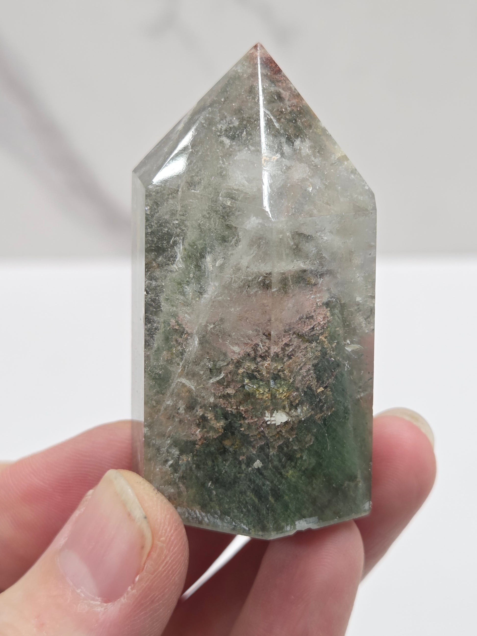 Hand holding a Garden Quartz crystal with a white background