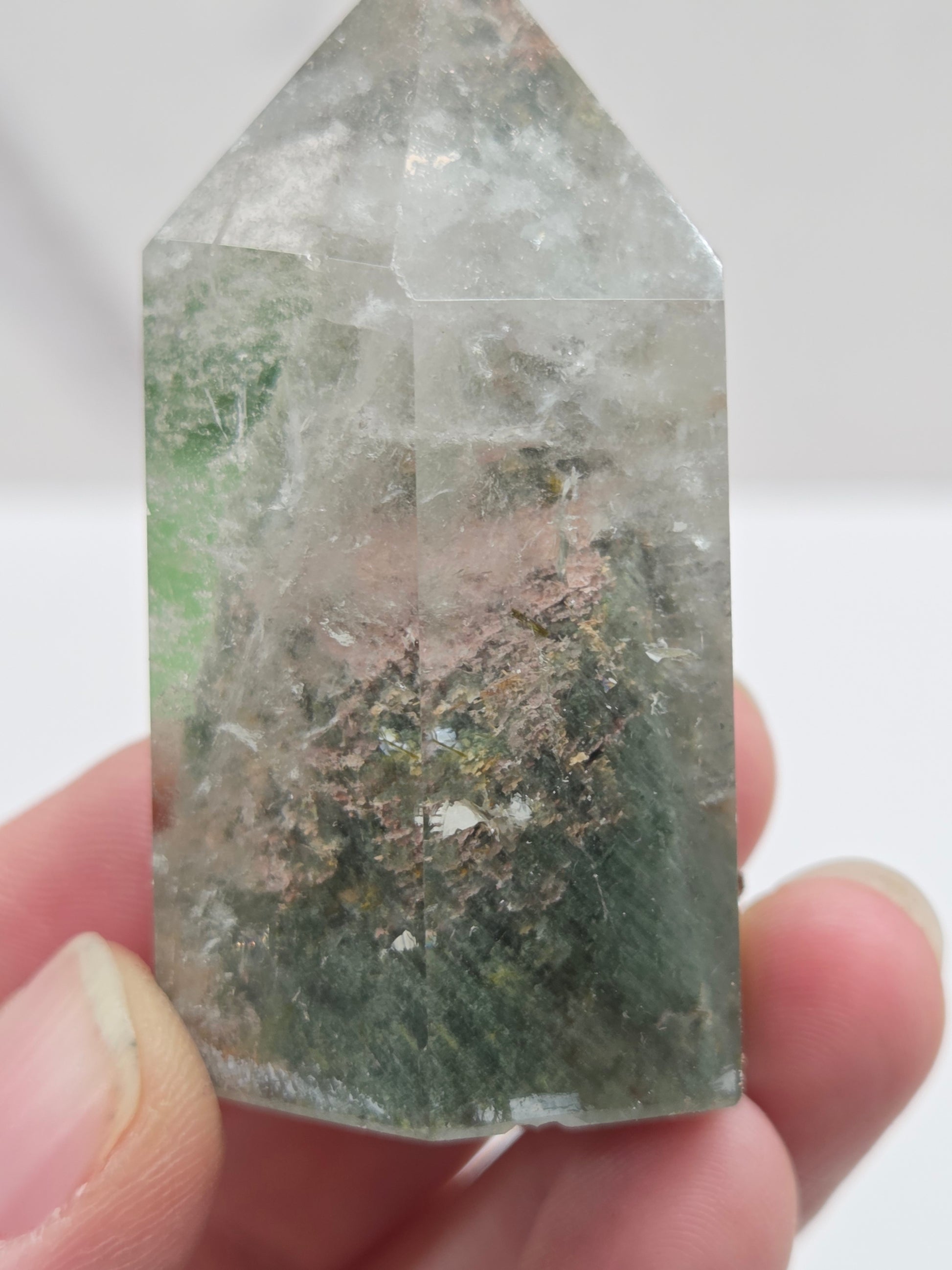 Clear crystal held by a hand against a white background